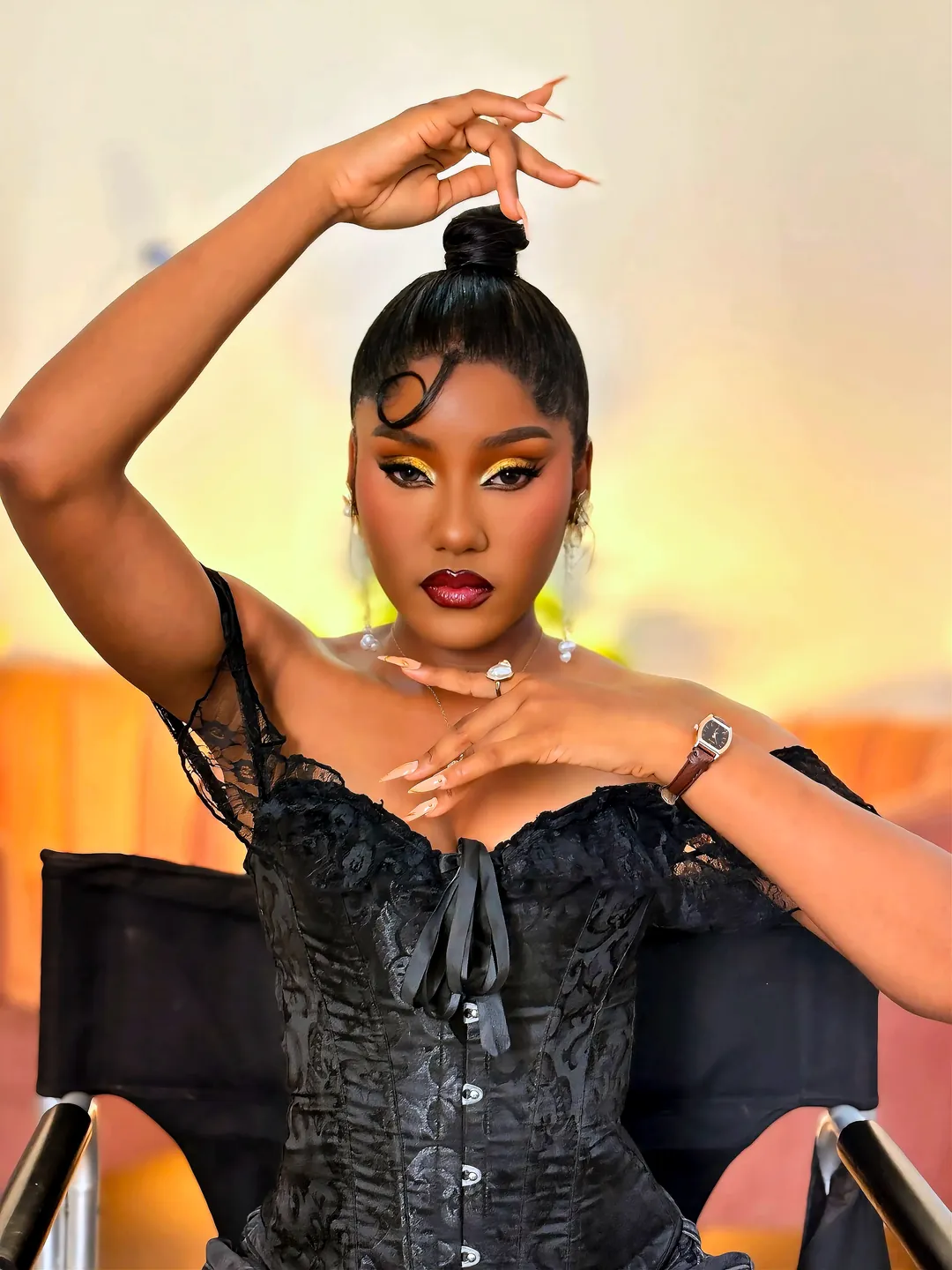 Black lace corset, one hand raised over a high bun
