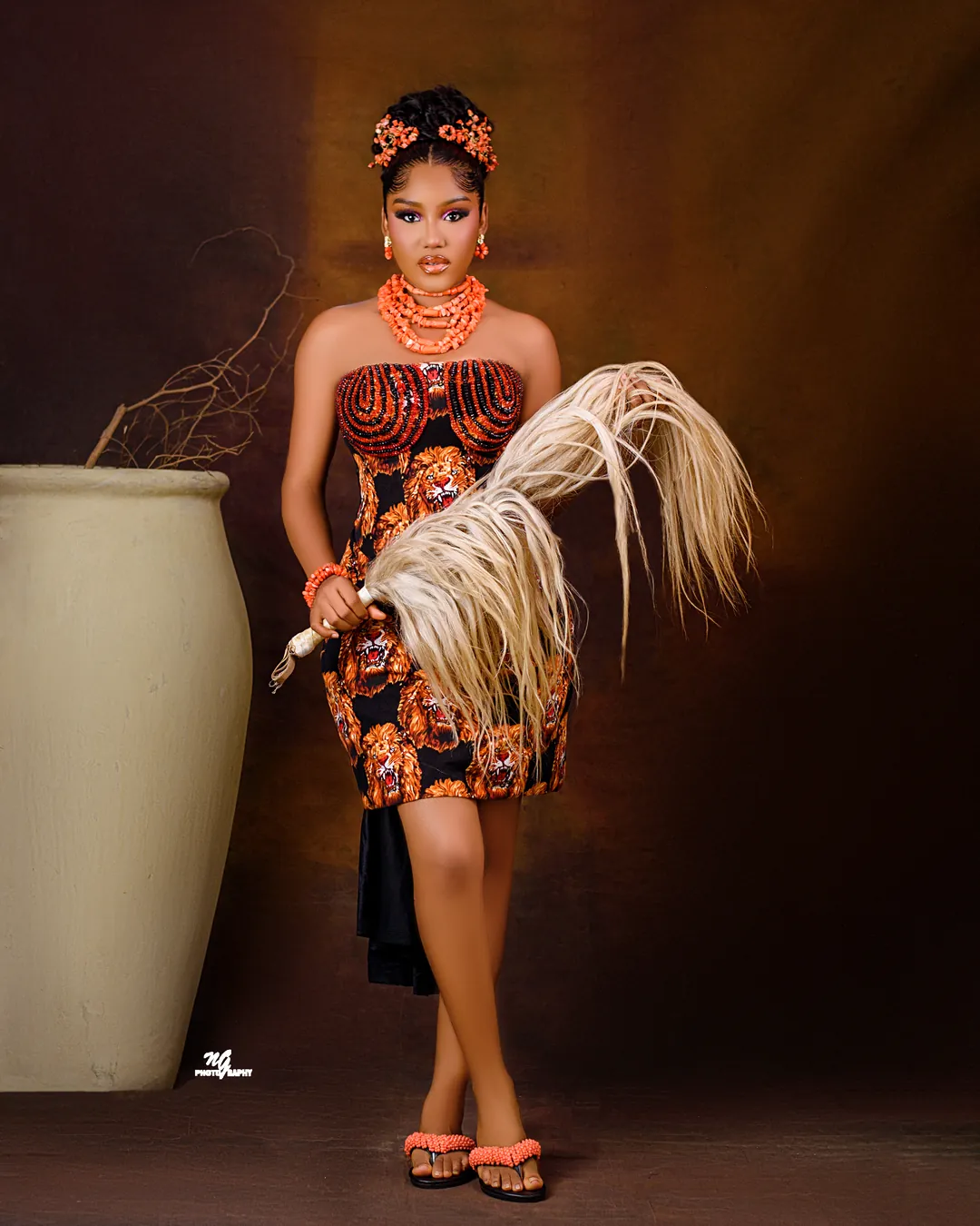 Full length in an Ankara corset dress, holding a horsetail