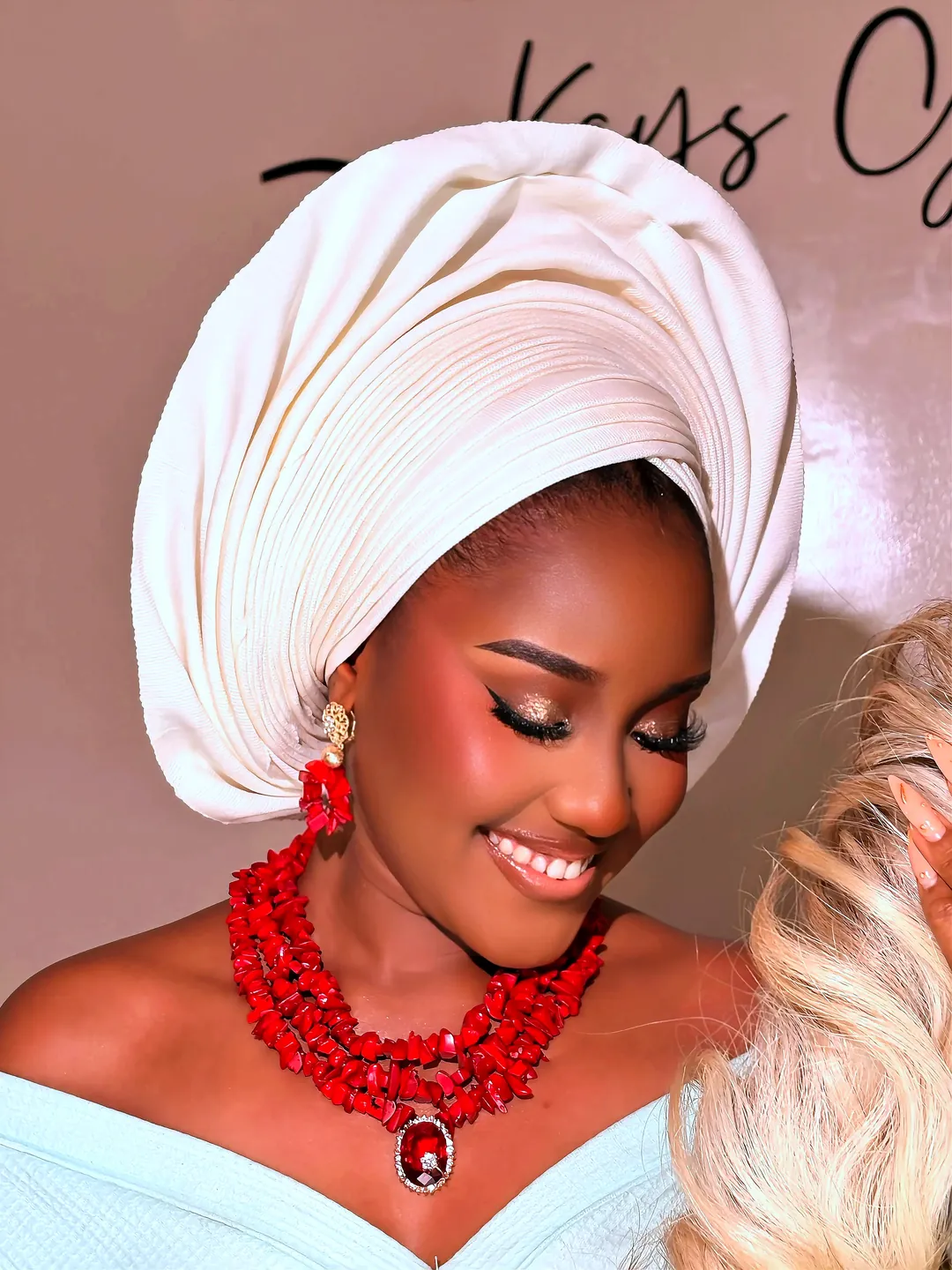 Smiling in a white gele and red coral beads