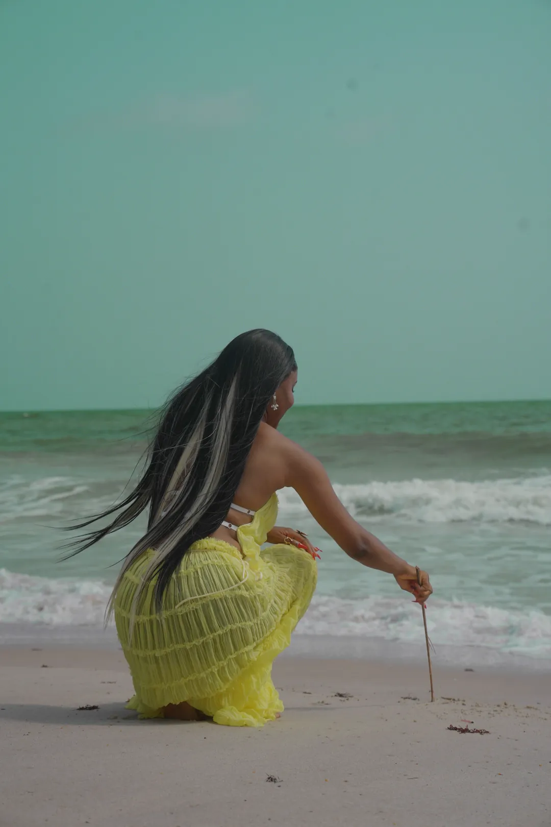 Kneeling by the water, tracing a line in the sand