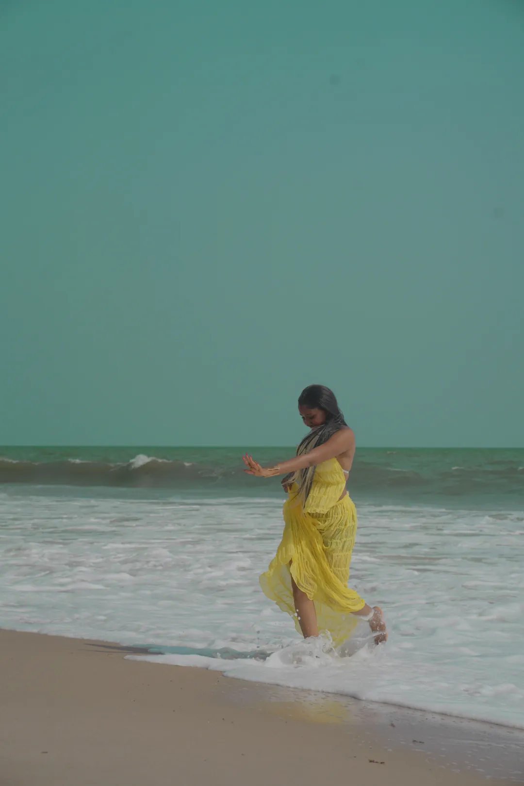 Stepping into the surf in the yellow gown